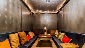 A narrow room with a long table and benches along the walls. - Q4 Hotel & Hostel (Long Island City)