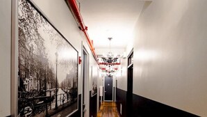 A hallway with wooden flooring, black and white walls, and a red pipe running along the ceiling. - Q4 Hotel & Hostel (Long Island City)