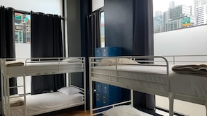 A dormitory room with bunk beds, a window with curtains, and a view of the cityscape. - Q4 Hotel & Hostel (Long Island City)