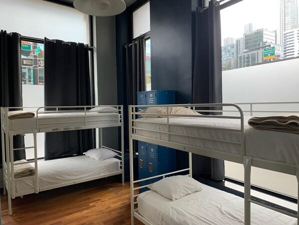 Un dormitorio con literas, una ventana con cortinas y vista a la ciudad.