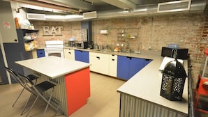 A compact kitchen with a central island, a sink, and a stove. - Q4 Hotel & Hostel (Long Island City)