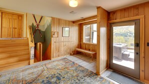 Un intérieur en bois avec un banc, une porte donnant sur l’extérieur et une fresque représentant une montagne sur le mur.