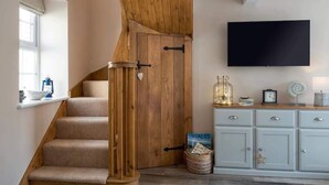 Un escalier avec des marches en bois et une porte en bois, un téléviseur à écran plat fixé au mur et un meuble bleu clair avec des tiroirs.