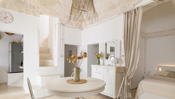 A bedroom with a bed, a bedside table, a mirror, and a window with curtains. - In Alto Mare by Wonderful Italy (Ostuni)