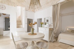 Un dormitorio con cama, mesita de noche, espejo y ventana con cortinas.