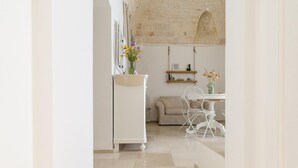 A modern kitchen with white cabinetry, a dining area with a white chair and table, and a hanging light fixture. - In Alto Mare by Wonderful Italy (Ostuni)