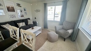 Un salon chaleureux avec un canapé, une table basse, un fauteuil à motifs et un petit pouf.