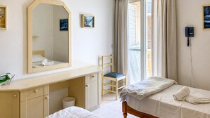A bedroom with two beds, a desk, a chair, a mirror, and a phone. - Seafront apartment in Gozo, Marsalforn (Zebbug)