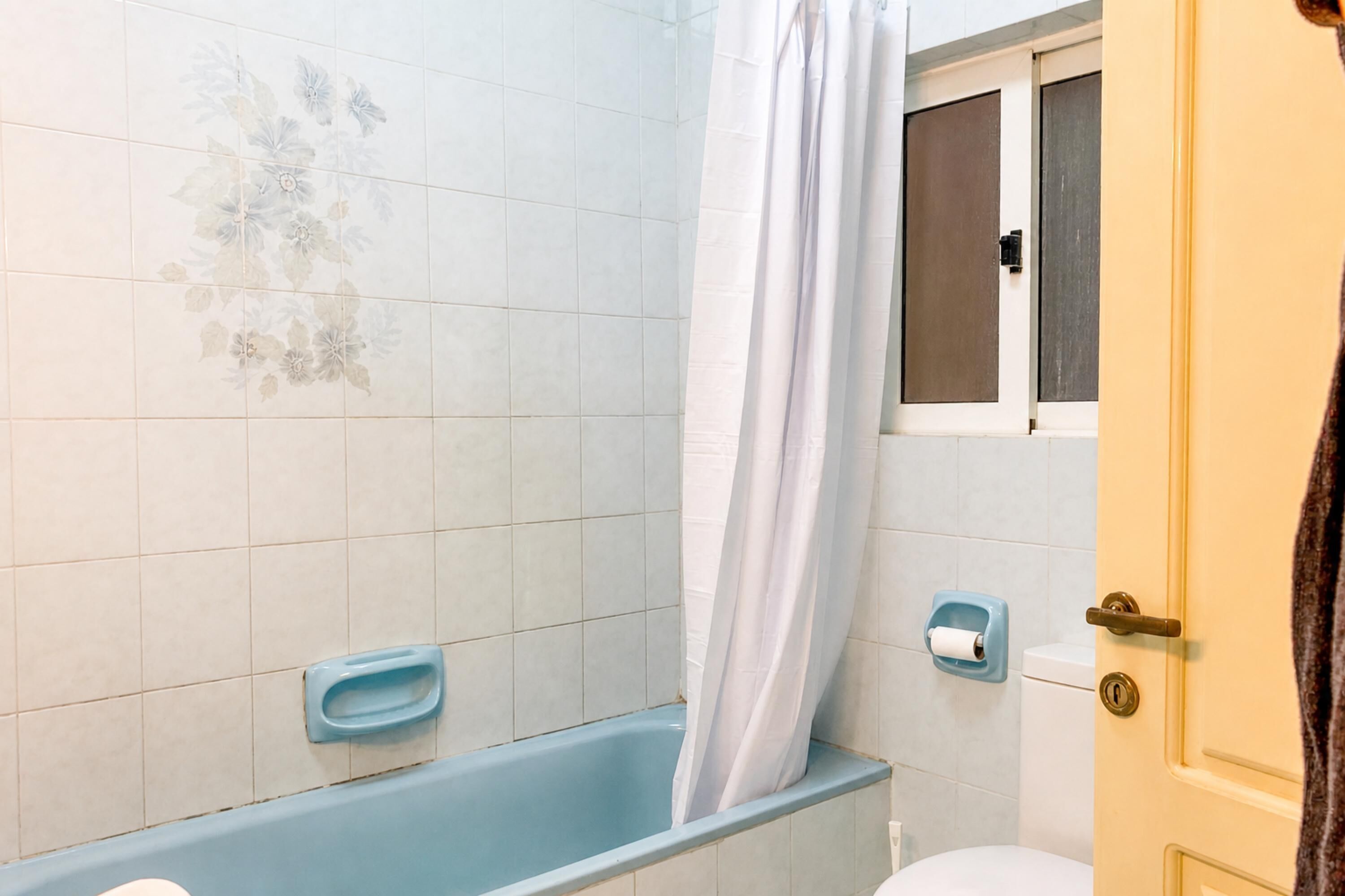 A bathroom with a bathtub, a toilet, a shower curtain, and a towel rack.