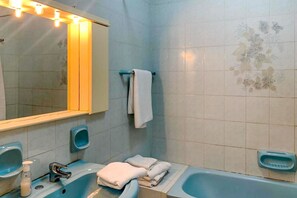 A bathroom with a blue sink, a mirror, a towel rack, and a bathtub.