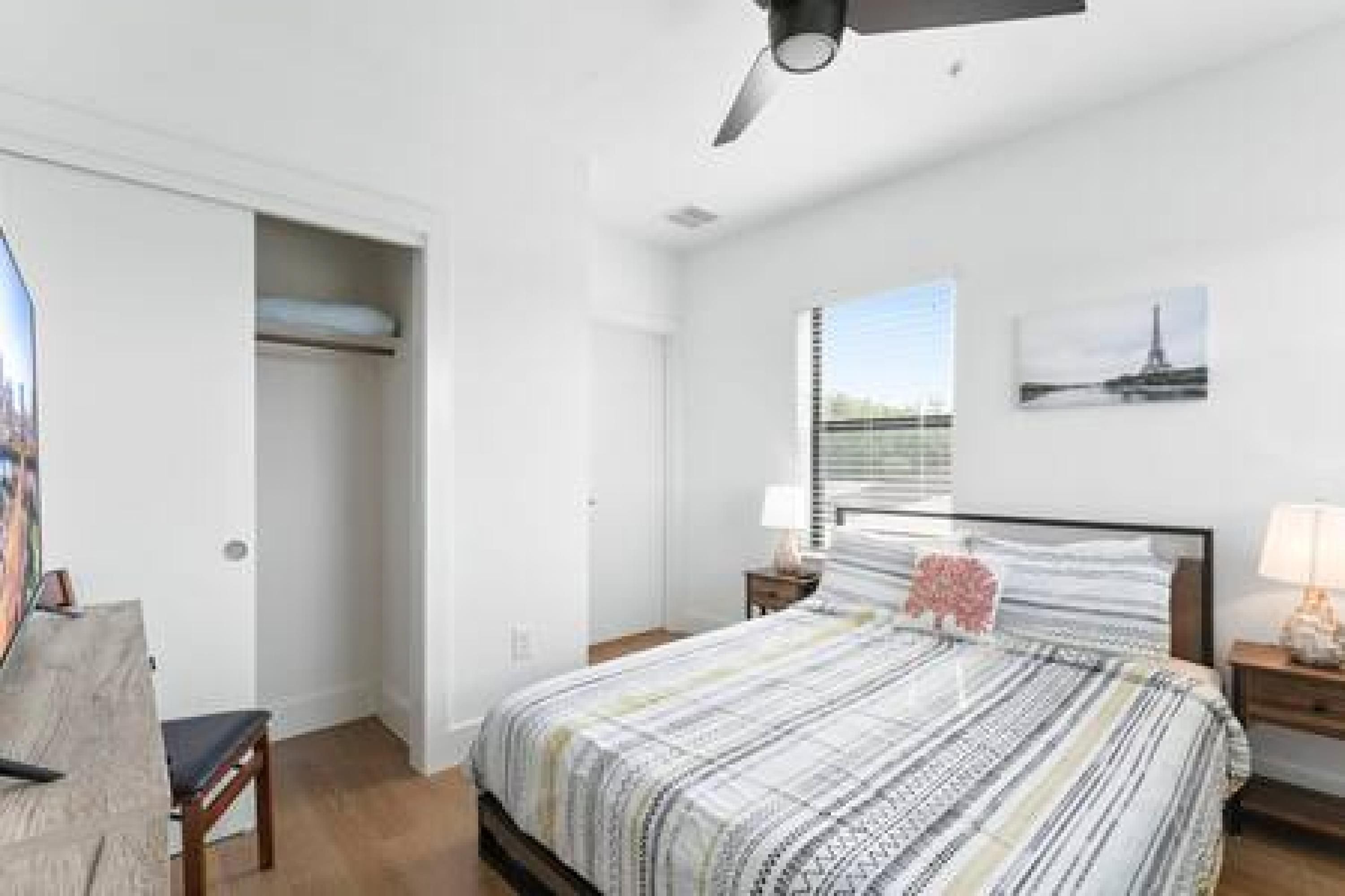 Une chambre à coucher avec un lit, une table de chevet et une fenêtre donnant sur un immeuble.