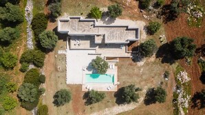 An aerial view of a modern house with a swimming pool, surrounded by trees and a rocky landscape. - Villa La Guaceta by Wonderful Italy (Carovigno)