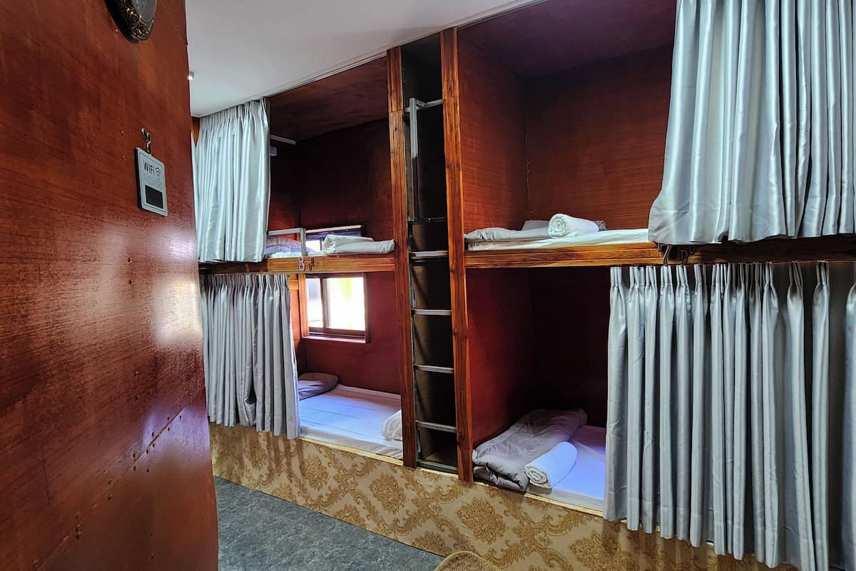 A room with bunk beds, a ladder, and curtains.