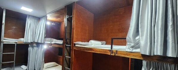 Ein Schlafraum mit Etagenbetten, Holzwänden und Metallgeländern.