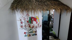 A room with a thatched roof, a wall with a colorful mural, and a door to the right. - VT SKY SHIP HOTEL (Vientiane)