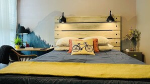 A bedroom with a bed, a nightstand, a chair, a desk, and a wall with a mountain painting. - Book NOW for Summer Fun! - Perfect for family! - Fully Loaded! - Fire Pit! (Portland)