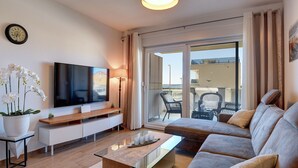 A modern living room with a flat-screen TV, a sofa, a coffee table, and a balcony with outdoor furniture. - Modern apartment with sea view (Medulin)