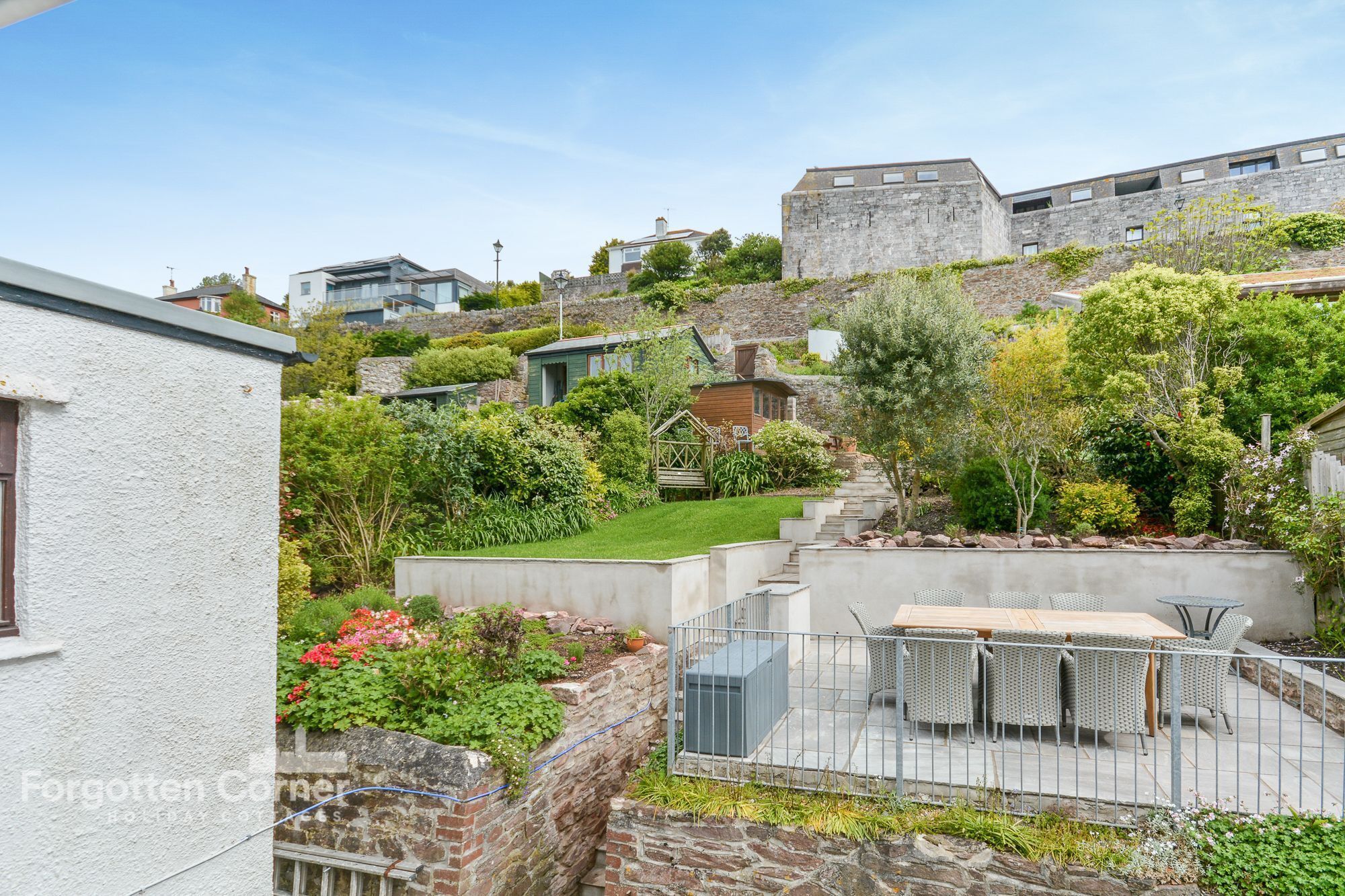 Un jardin aménagé sur le toit, avec un espace salon, des murs en pierre et une variété de plantes.