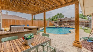 Ein überdachter Außenbereich mit Pool, Holzdeck, Sitzgelegenheiten und Grill.