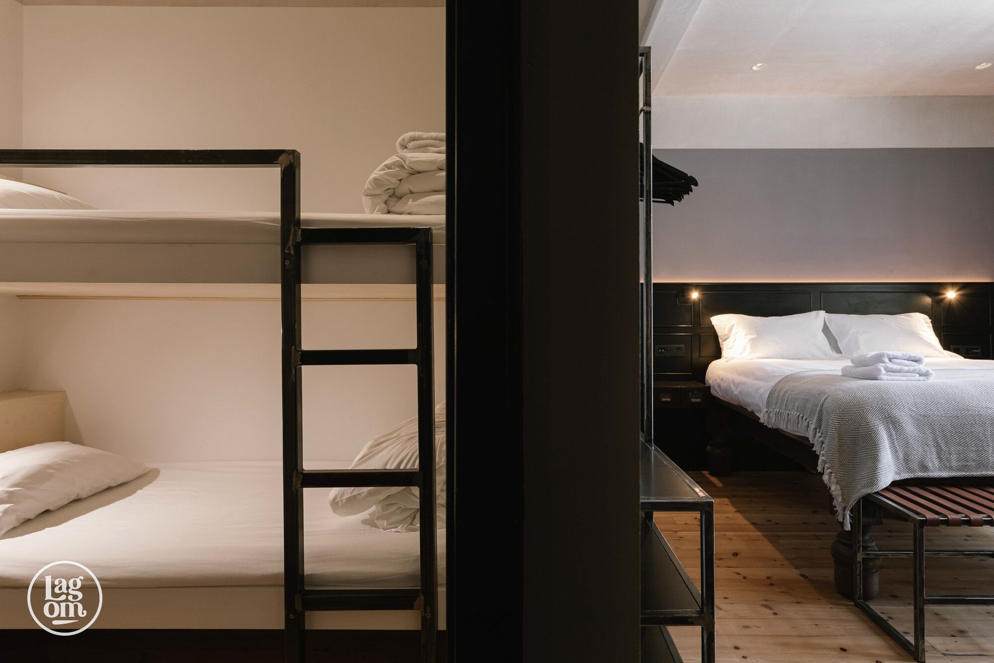 A bunk bed room with a ladder, a bedside table, and a bed with white bedding.