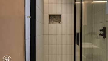 A tiled shower area with a glass door and a small square tile feature on the wall.