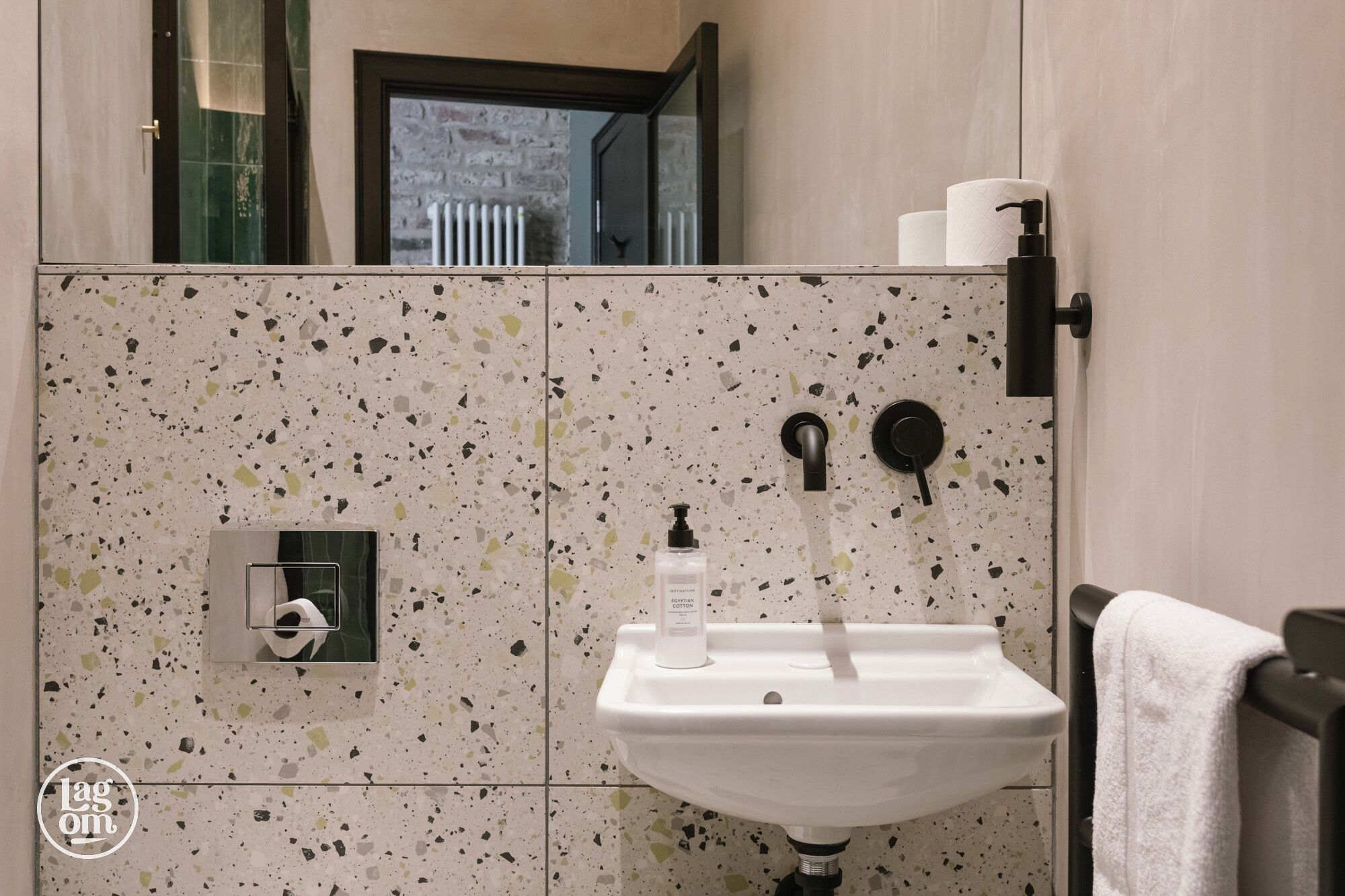 A bathroom with a white sink, a hand soap dispenser, and a towel hanging on the right.