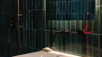 Une salle de bain avec un lavabo blanc, des murs recouverts de carreaux bleu foncé et un espace douche.