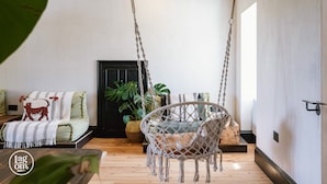 A cozy living room with a macramé swing chair, a sofa with patterned cushions, and a potted plant. - Stay Lagom Lodge (Ballycastle)