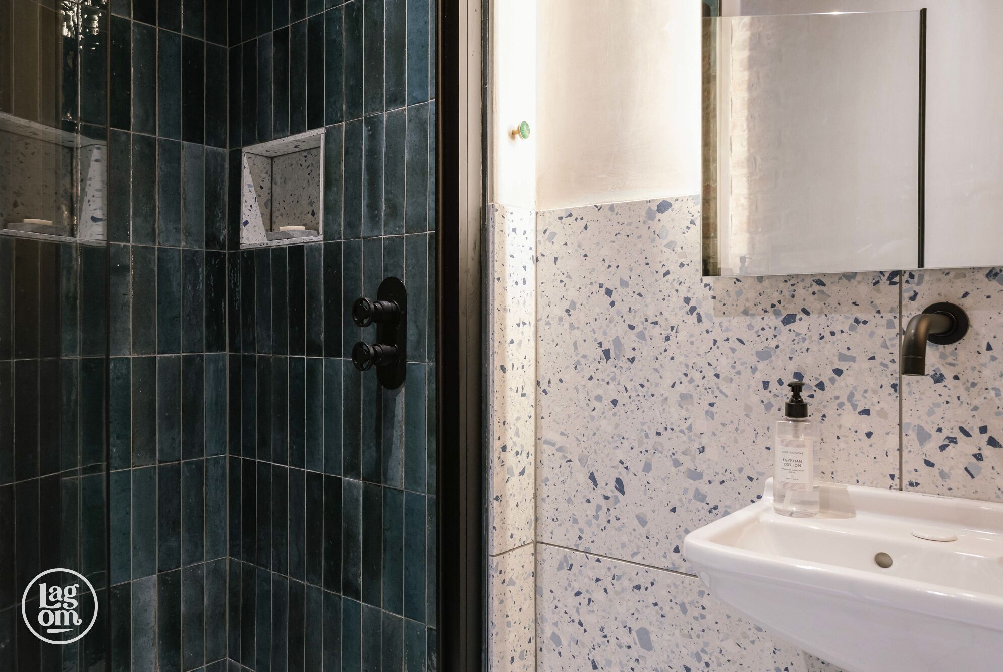 A bathroom with dark blue tiles, a white sink with a speckled backsplash, and a mirror above the sink.