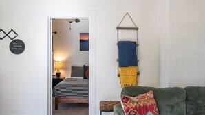 A cozy room with a bed, a green sofa, and a hanging laundry rack. - Artful Retreat Near GJs Main St: Dog-Friendly (Grand Junction)