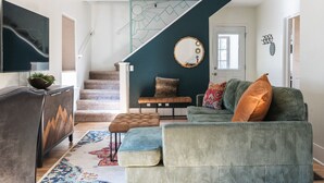 A living room with a sofa, ottoman, and a staircase leading to another level. - Artful Retreat Near GJs Main St: Dog-Friendly (Grand Junction)