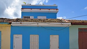 Ein zweigeschossiges Gebäude mit blauer Fassade, weißen Türen und einem Ziegeldach.