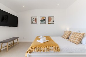 A modern bedroom with a bed, a bench, and three abstract art pieces on the wall.
