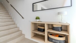 A staircase with beige tiles, a wooden console table with baskets, a potted plant, and a mirror on the wall.