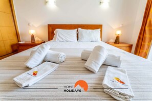 A hotel room with a neatly made bed, two bedside lamps, and a view of the room's interior.