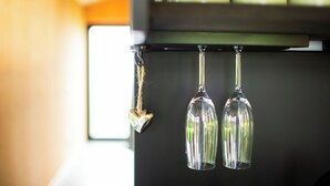 A coffee machine with a hanging heart-shaped ornament and two wine glasses.
