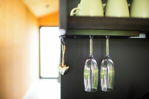 A coffee machine with a hanging heart-shaped ornament and two wine glasses.