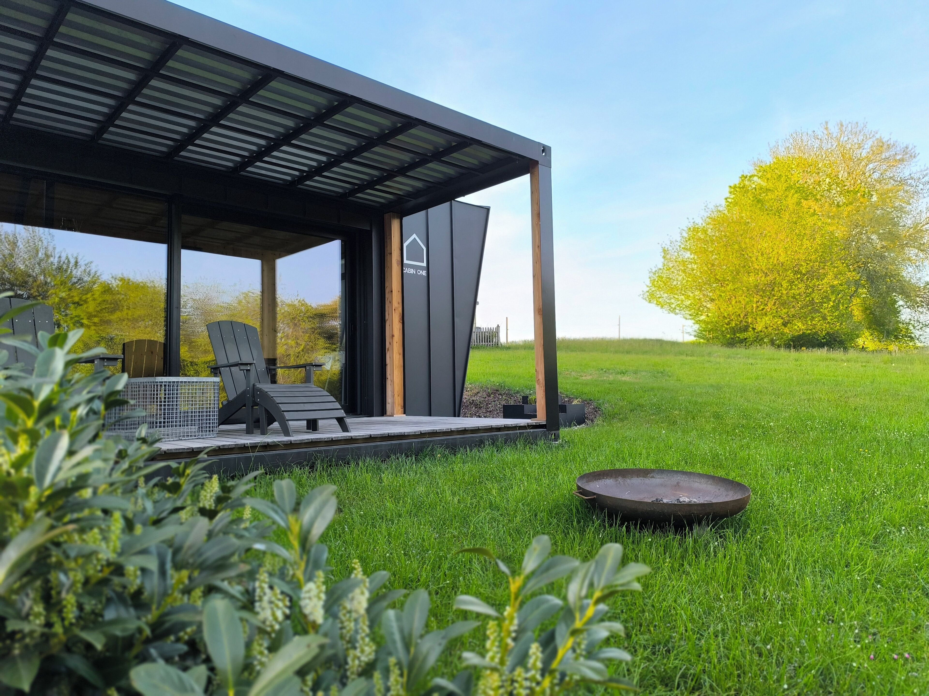 Een modern buitenzitgedeelte met een overdekte patio, een lounge stoel en een bijzettafeltje.