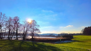 A serene landscape with a clear sky, a body of water, and a grassy field.