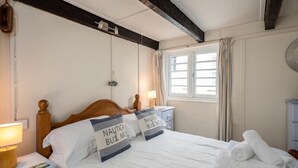 A neatly made bed with two pillows, a bedside lamp, and a window with curtains. - St Samson (Port Isaac)