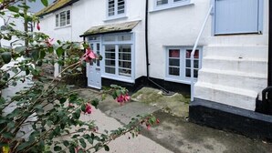 A traditional white building with blue shutters and a small attached structure with a door. - St Samson (Port Isaac)
