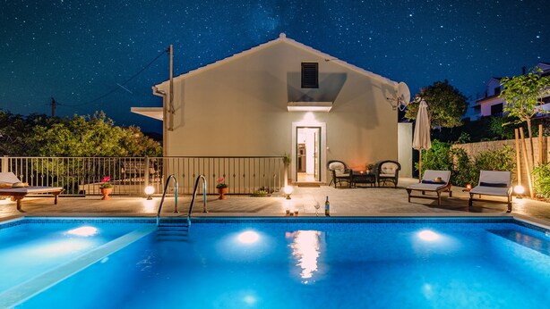 En swimmingpool med liggestole og en bygning i baggrunden.