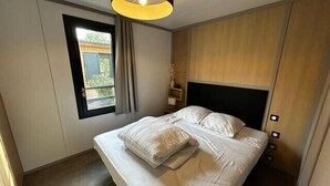 Un dormitorio con cama, ventana y luz en el techo.