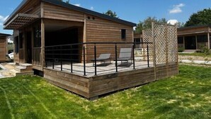 Una cabaña de madera con un porche cubierto y un área de terraza cercada.