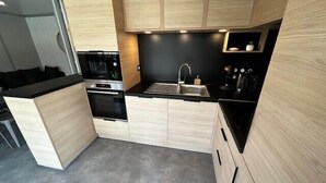 Una cocina moderna con armarios de madera clara, encimeras negras y electrodomésticos de acero inoxidable.