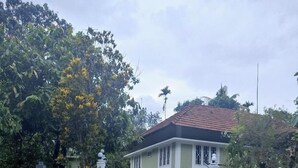 A house with a paved pathway leading to the entrance, surrounded by lush greenery and a clear sky. - 	“Your Family’s Perfect Getaway by the Riverside!” (Mankulam)