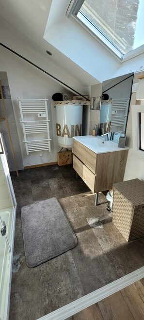 A modern bathroom with a skylight, a vanity with a mirror, and a towel rack. - Le 6 Bis Avec Jardinet (Guémené-Penfao)