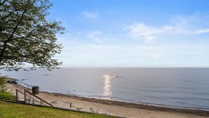 Een strand met een houten looppad naar de kust, een grasveld op de voorgrond en een heldere lucht.
