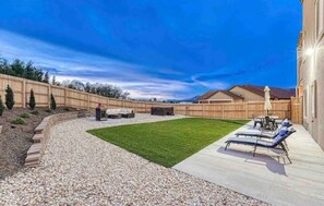 A backyard with a patio, a lawn, and a wooden fence. - Rooftop Patio, Hot Tub, EV charging, Mtn views, close to AFA! (Palmer Lake)
