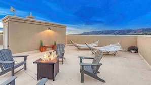 A rooftop terrace with a fire pit, Adirondack chairs, and a hammock. - Rooftop Patio, Hot Tub, EV charging, Mtn views, close to AFA! (Palmer Lake)